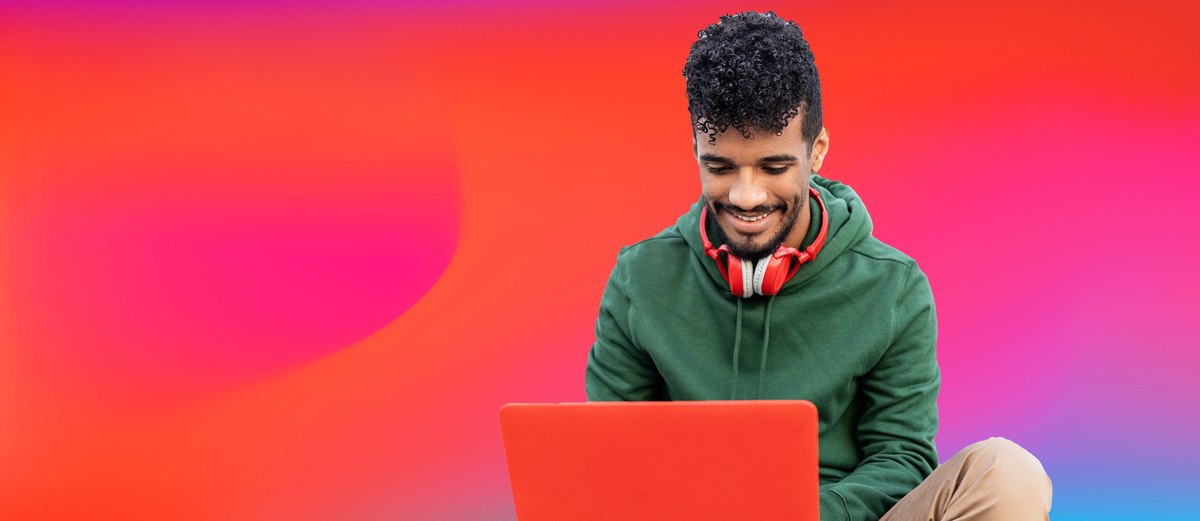 dark curly haired guy with green hoodie working on his laptop